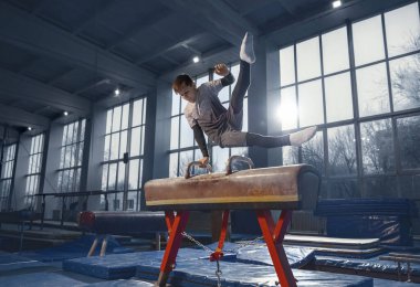 Spor salonunda küçük bir erkek jimnastikçi, esnek ve aktif.