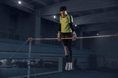 Spor salonunda küçük bir erkek jimnastikçi, esnek ve aktif.