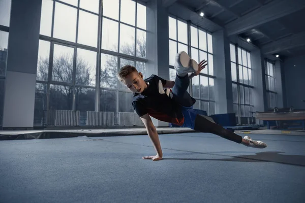 Little male gymnast training in gym, flexible and active