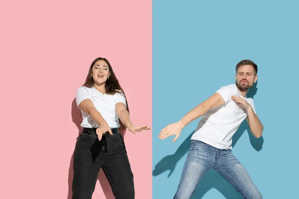 Joven hombre y mujer emocional sobre fondo rosa y azul — Foto de Stock