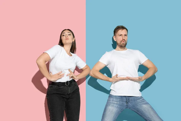 Young emotional man and woman on pink and blue background — Stock Photo, Image