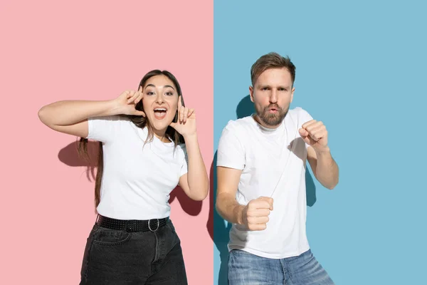 Jovem homem emocional e mulher no fundo rosa e azul — Fotografia de Stock