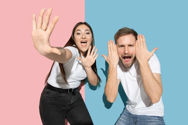 Junge emotionale Mann und Frau auf rosa und blauen Hintergrund — Stockfoto