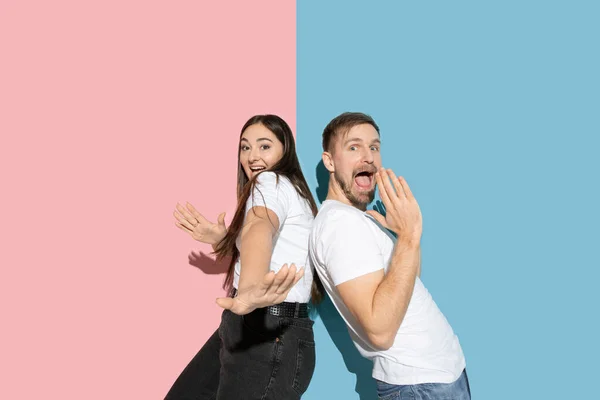 Young emotional man and woman on pink and blue background — Stock Photo, Image