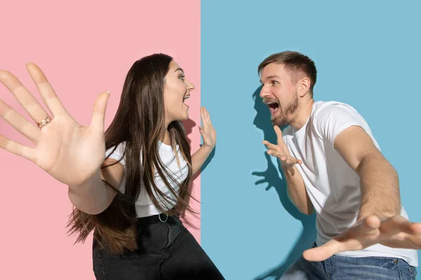 Ung emotionell man och kvinna på rosa och blå bakgrund — Stockfoto