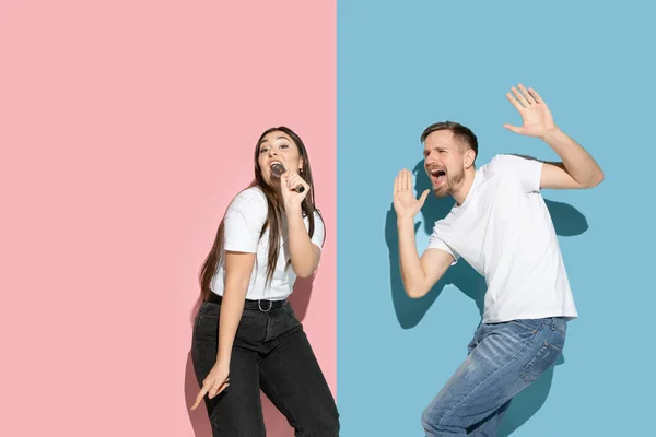 Jeune homme et femme émotionnelle sur fond rose et bleu — Photo