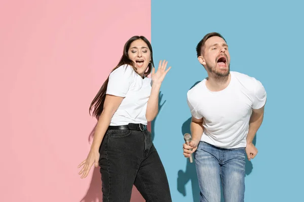 Młody emocjonalny mężczyzna i kobieta na różowym i niebieskim tle — Zdjęcie stockowe