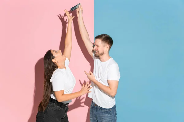 Giovane uomo e donna emotivo su sfondo rosa e blu — Foto Stock