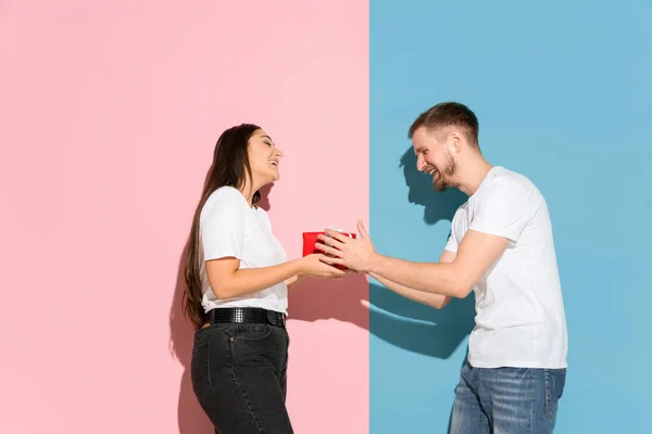 Молодой эмоциональный мужчина и женщина на розовом и синем фоне — стоковое фото