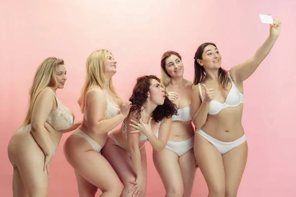 Portrait of beautiful plus size young women posing on pink background — 스톡 사진