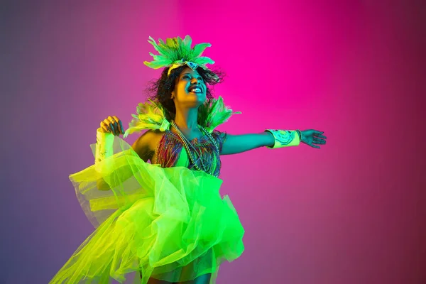 Hermosa mujer joven en traje de carnaval y mascarada en el fondo del estudio de gradiente en luz de neón — Foto de Stock