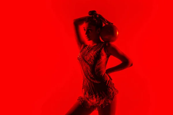 Νεαρή ευέλικτη γυμνάστρια απομονωμένη σε κόκκινο φόντο στούντιο — Φωτογραφία Αρχείου