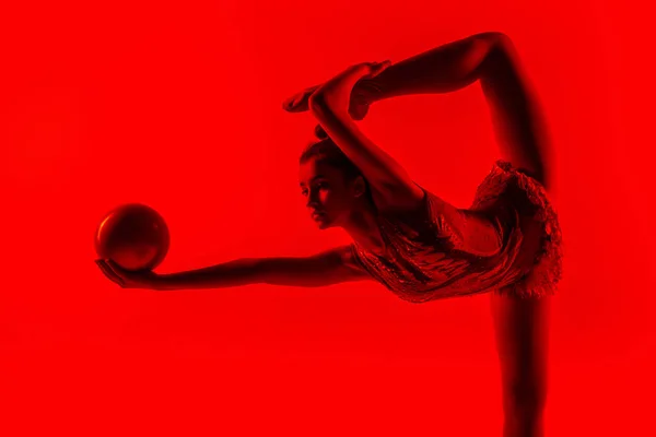 Giovane ginnasta femminile flessibile isolato su sfondo rosso studio — Foto Stock