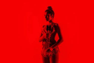 Genç esnek bayan jimnastikçi kırmızı stüdyo arka planında izole edilmiş.