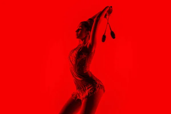 Jovem ginasta feminino flexível isolado no fundo do estúdio vermelho — Fotografia de Stock