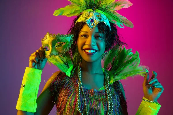 Hermosa mujer joven en traje de carnaval y mascarada en el fondo del estudio de gradiente en luz de neón — Foto de Stock