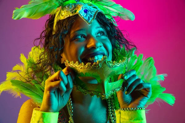 Hermosa mujer joven en traje de carnaval y mascarada en el fondo del estudio de gradiente en luz de neón — Foto de Stock