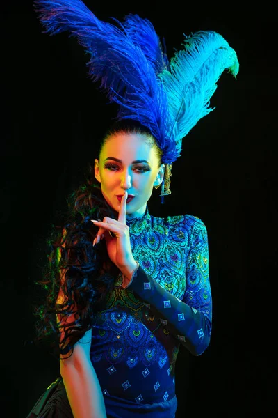 Hermosa mujer joven en carnaval y disfraz de mascarada en luces de neón de colores sobre fondo negro — Foto de Stock