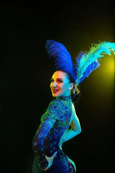 Krásná mladá žena v karnevalu a maškarní kostým v barevných neonových světlech na černém pozadí — Stock fotografie