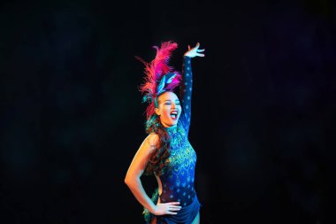 Karnaval ve maskeli balo kostümlü güzel bir kadın. Siyah arka planda renkli neon ışıklar.