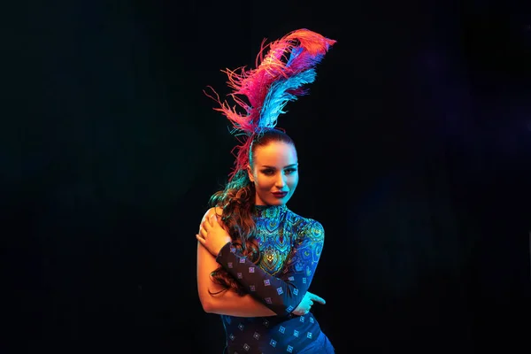 Belle jeune femme en costume de carnaval et de mascarade dans des néons colorés sur fond noir — Photo