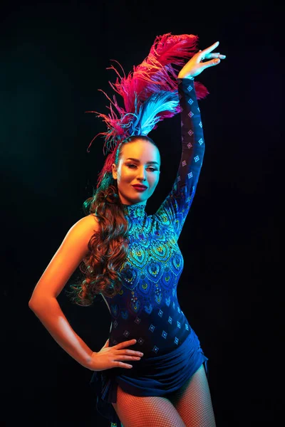 Schöne junge Frau in Karneval und Maskerade Kostüm in bunten Neonlichtern auf schwarzem Hintergrund — Stockfoto