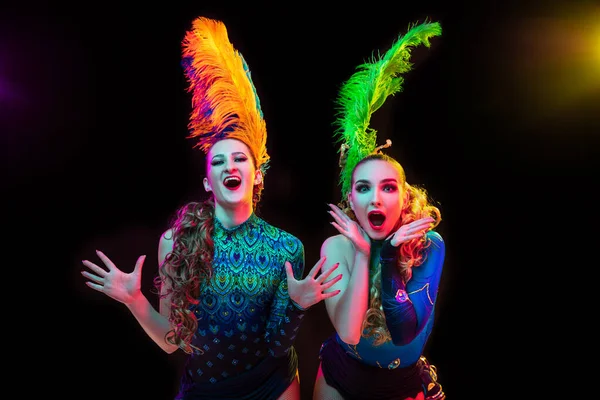 Mooie jonge vrouwen in carnaval en maskerade kostuum in kleurrijke neon lichten op zwarte achtergrond — Stockfoto