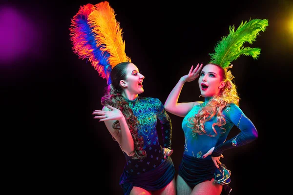 Gyönyörű fiatal nők karnevál és álarcosbál jelmez színes neon fények fekete háttér — Stock Fotó
