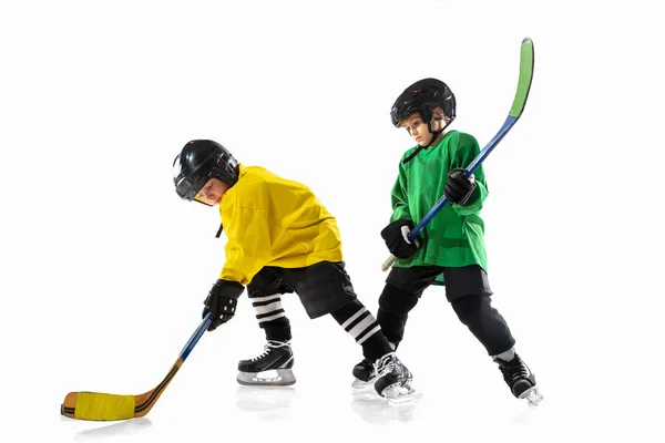 Kleine Hockeyspieler mit den Stöcken auf dem Eis und weißem Studiohintergrund — Stockfoto