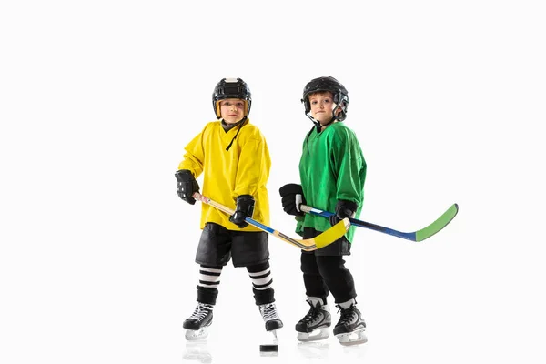 Kleine hockeyspeelsters met de stokken op de ijsbaan en witte studioachtergrond — Stockfoto