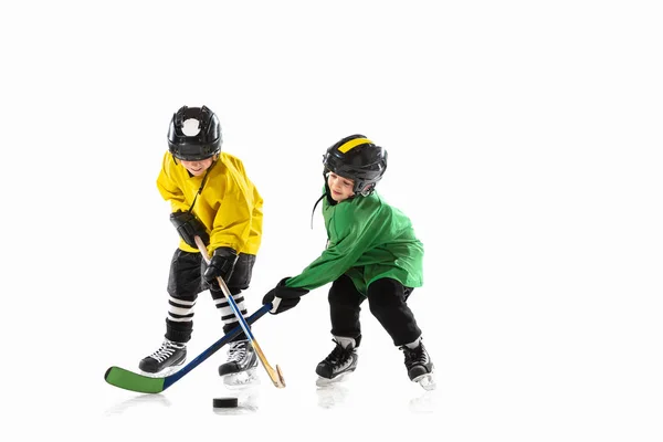 Little hockey players with the sticks on ice court and white studio background — Stock Photo, Image