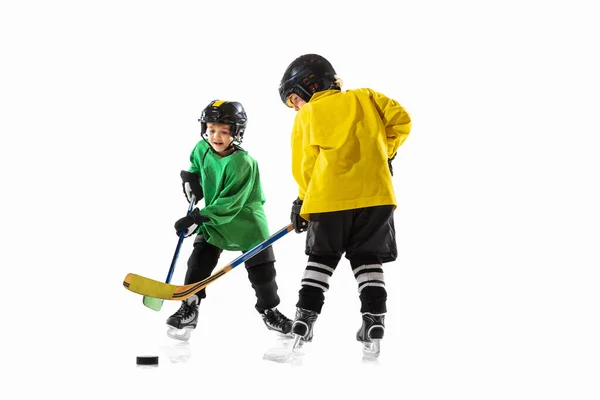 Pequeños jugadores de hockey con palos en pista de hielo y fondo de estudio blanco —  Fotos de Stock