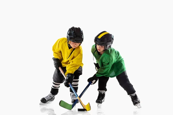 Kleine Hockeyspieler mit den Stöcken auf dem Eis und weißem Studiohintergrund — Stockfoto