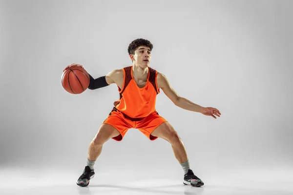Jovem jogador de basquete treinando isolado no fundo do estúdio branco — Fotografia de Stock