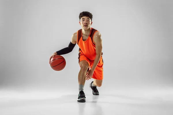 Jovem jogador de basquete treinando isolado no fundo do estúdio branco — Fotografia de Stock