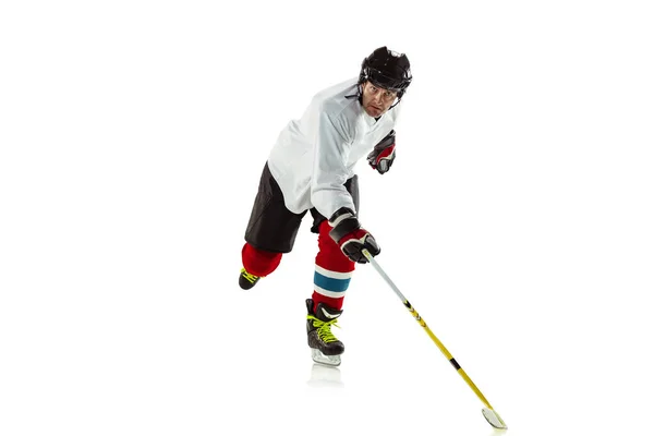 Young male hockey player with the stick on ice court and white background — Stock Photo, Image