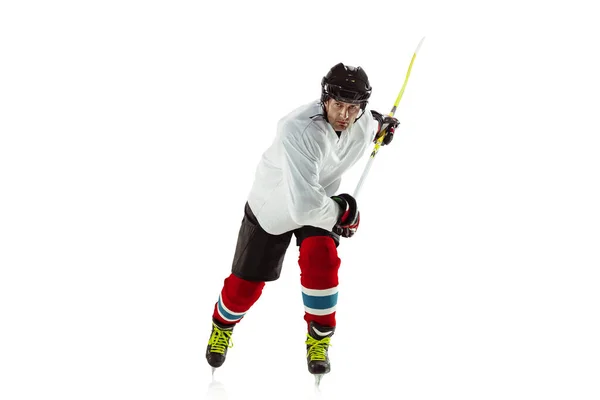 Young male hockey player with the stick on ice court and white background — Stock Photo, Image