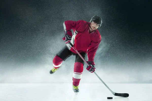 Jugador de hockey masculino con el palo en la pista de hielo y fondo oscuro — Foto de Stock