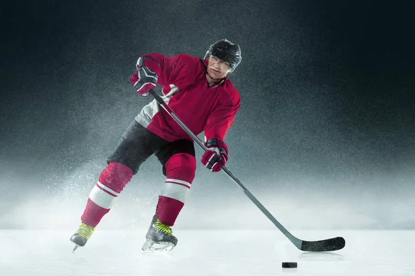 Jugador de hockey masculino con el palo en la pista de hielo y fondo oscuro — Foto de Stock