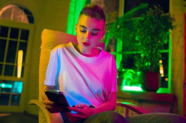 Neon ışıklı iç mekan içinde yakışıklı genç bir kadının sinematik portresi.