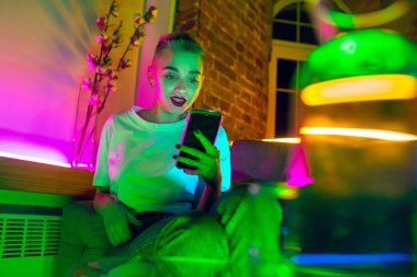 Neon ışıklı iç mekan içinde yakışıklı genç bir kadının sinematik portresi.
