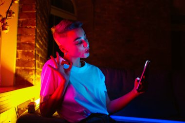 Neon ışıklı iç mekan içinde yakışıklı genç bir kadının sinematik portresi.