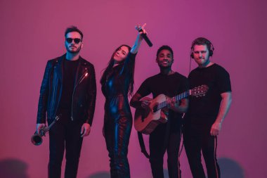 Genç çok ırklı müzisyenlerden oluşan bir grup, pembe arka planda neon ışıkta dans ederek grup kurdu.