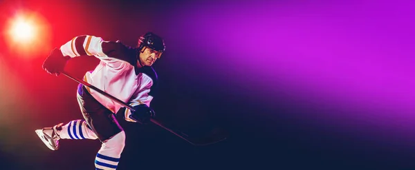 Man hockey speler met de stok op de ijsbaan en donker neon gekleurde achtergrond — Stockfoto