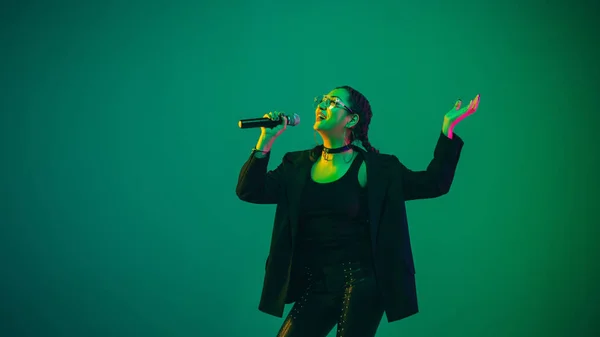 Retrato femenino de cantante caucásica aislado en fondo de estudio verde en luz de neón —  Fotos de Stock