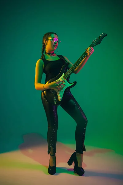 Portrait de guitariste féminine caucasienne isolé sur fond de studio vert au néon — Photo