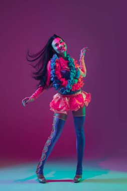 Attractive hawaiian brunette model on purple studio background in neon light