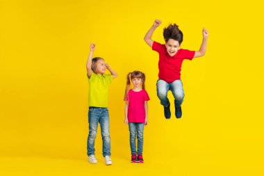 Happy children playing and having fun together on yellow studio background