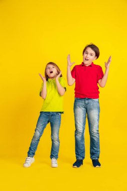 Happy children playing and having fun together on yellow studio background