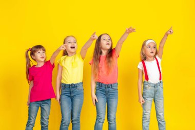 Happy children playing and having fun together on yellow studio background
